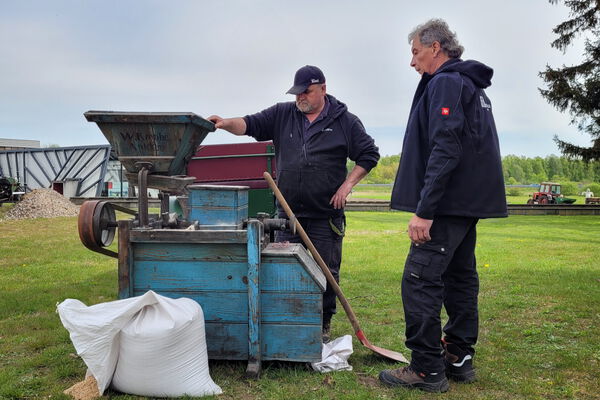 Zwei Männer auf dem Freigelände des Agroneum bei der Vorführung einer Schrotmühle.