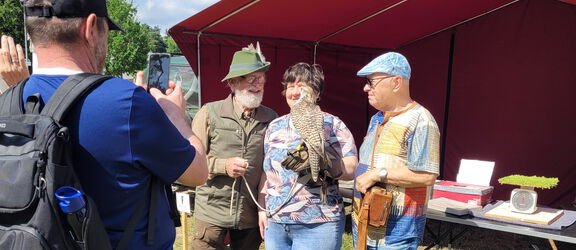 4 Personen auf dem Außengelände des Agroneum, eine Person hält einen Falken auf dem Arm.