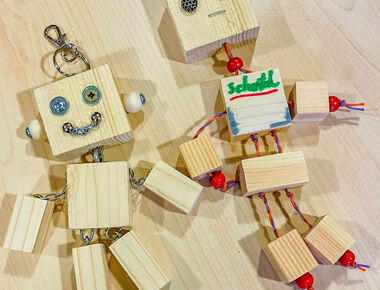 Zwei selbstgebastelte Schlüsselanhänger als Holzfiguren mit Gesichtern