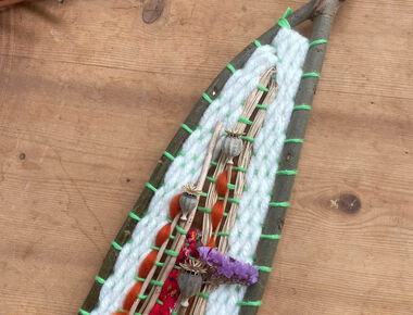 Ein selbst gebastelter Webrahmen aus Zweigen und weiteren Naturmaterialien