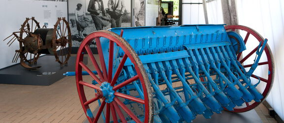 ein blaues agrarhistorisches Gerät mit 2 großen, roten Rädern