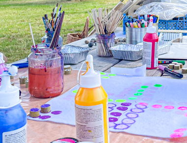 Ein Tisch mit diversen Farbtuben, Pinseln, Stiften und weiterem Bastelmaterial