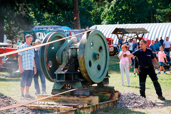 Mehrere Personen sehen bei der Vorführung einer agrarhistorischen Maschine zu.