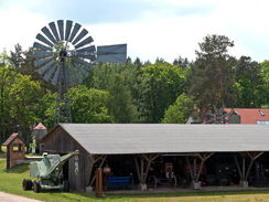 Rinderoffenstall auf dem Gelände des Agroneum, dahinter ein altes Windrad