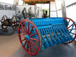 ein blaues agrarhistorisches Gerät mit 2 großen, roten Rädern
