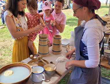 1 Mitarbeiterin des Agroneum macht den Workshop Buttern mit 2 Frauen und 2 kleinen Mädchen.