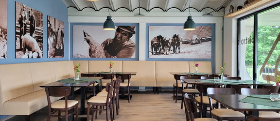 Innenaufnahme des Restaurants Pott un Pann mit einigen Tischen und Stühlen und einer großen Sitzbank
