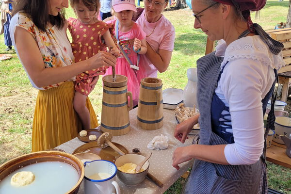 1 Mitarbeiterin des Agroneum macht den Workshop Buttern mit 2 Frauen und 2 kleinen Mädchen.