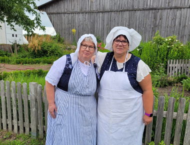Zwei Mitarbeiterinnen des Agroneum, bekleidet mit einer Tracht im Museumsgarten.