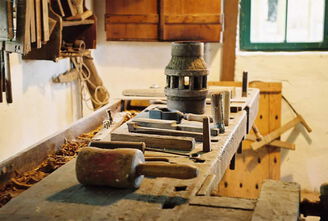 Einige historische Werkzeuge liegen in einer Werkstatt auf einer Werkbank aus Holz